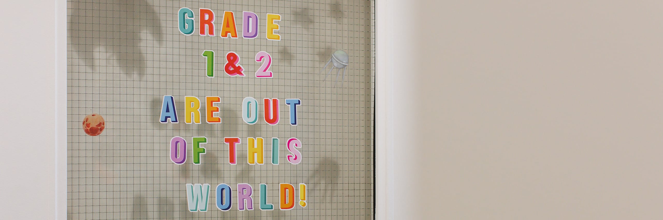Colourful letter board on a classroom wall spelling out "Grade 1 & 2 Are Out of This World"