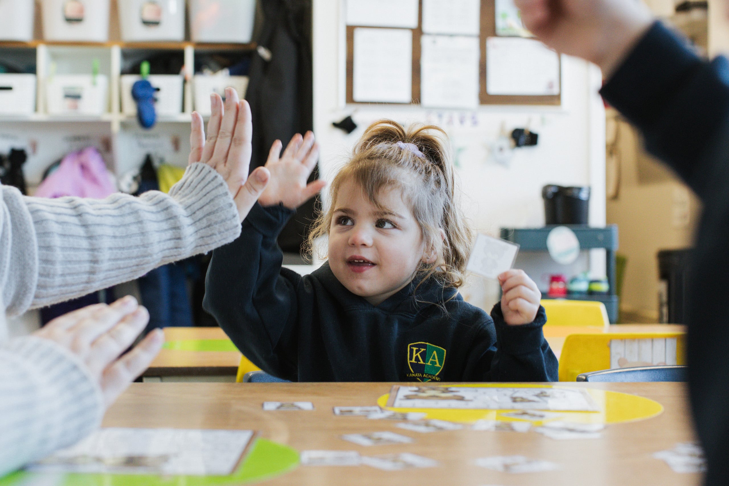 Student in a Kanata Academy uniform giving a high five in a classroom setting